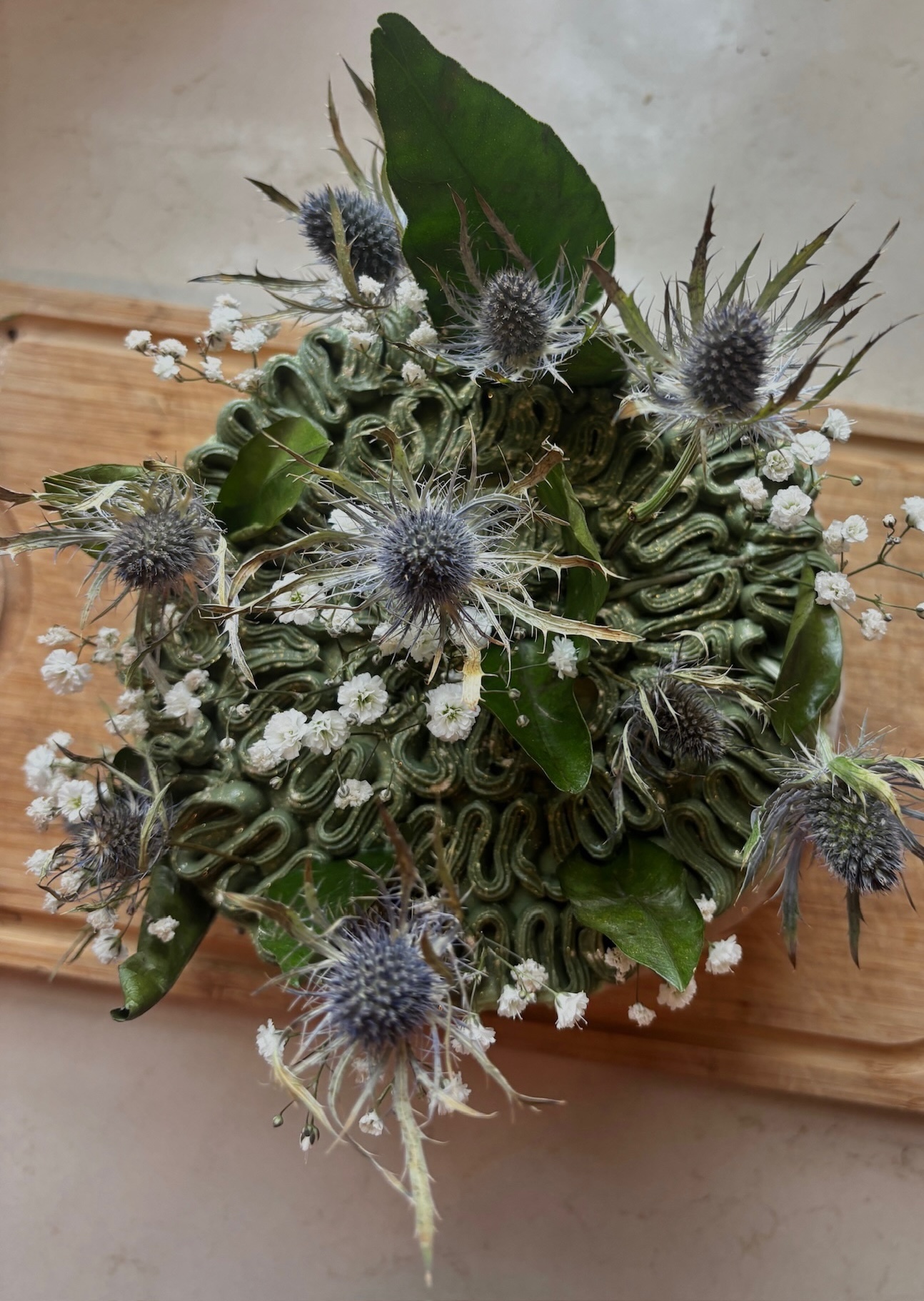 Green piped cake from above with thistles and baby's breath