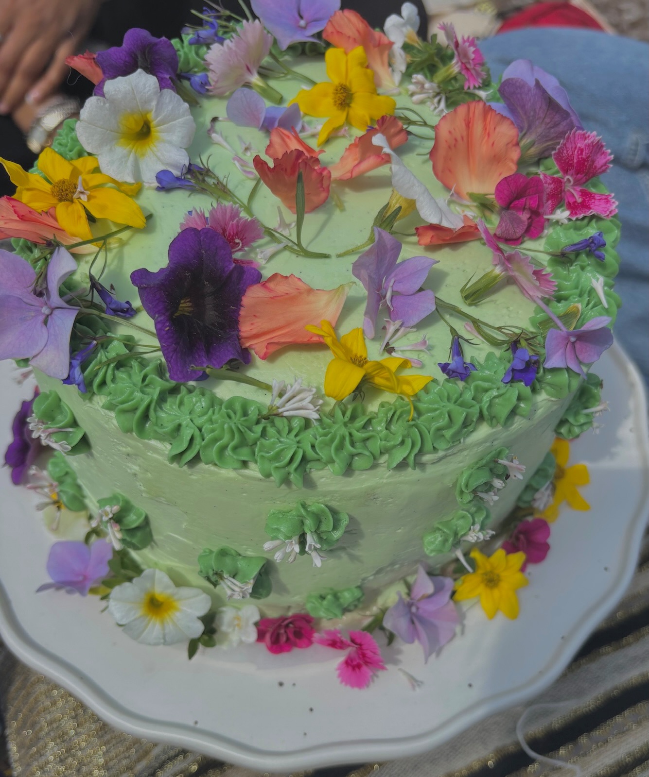 Green garden cake with vibrant purple and orange flowers