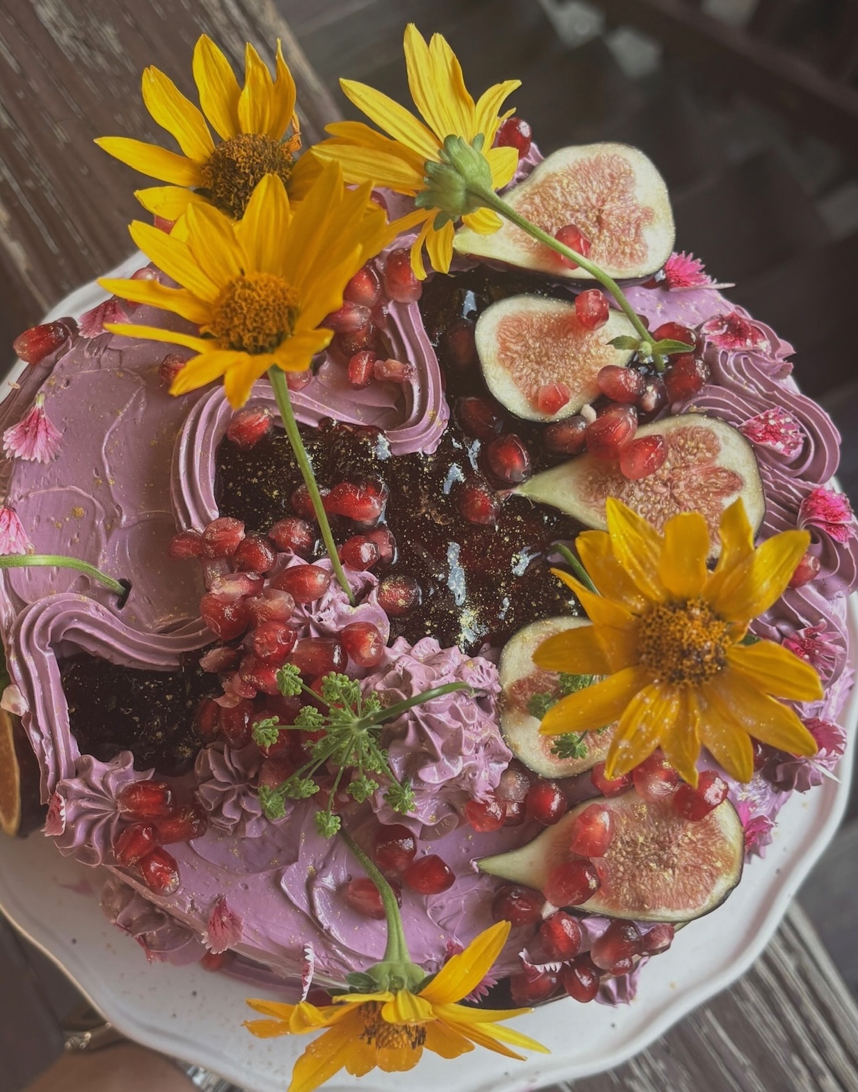 Purple cake top-down with sunflowers, figs and pomegranate