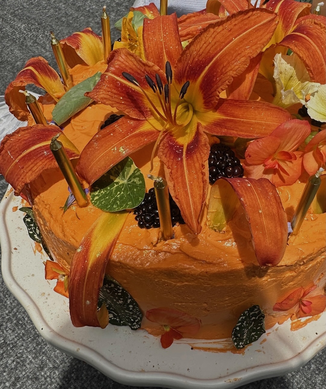 Orange lily birthday cake close-up with gold candles