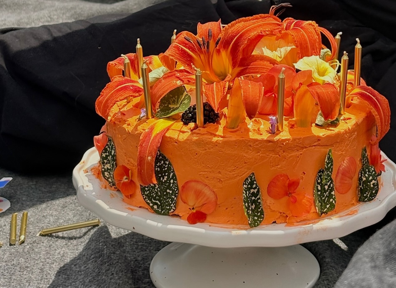 Vibrant orange lily cake on pedestal, full view